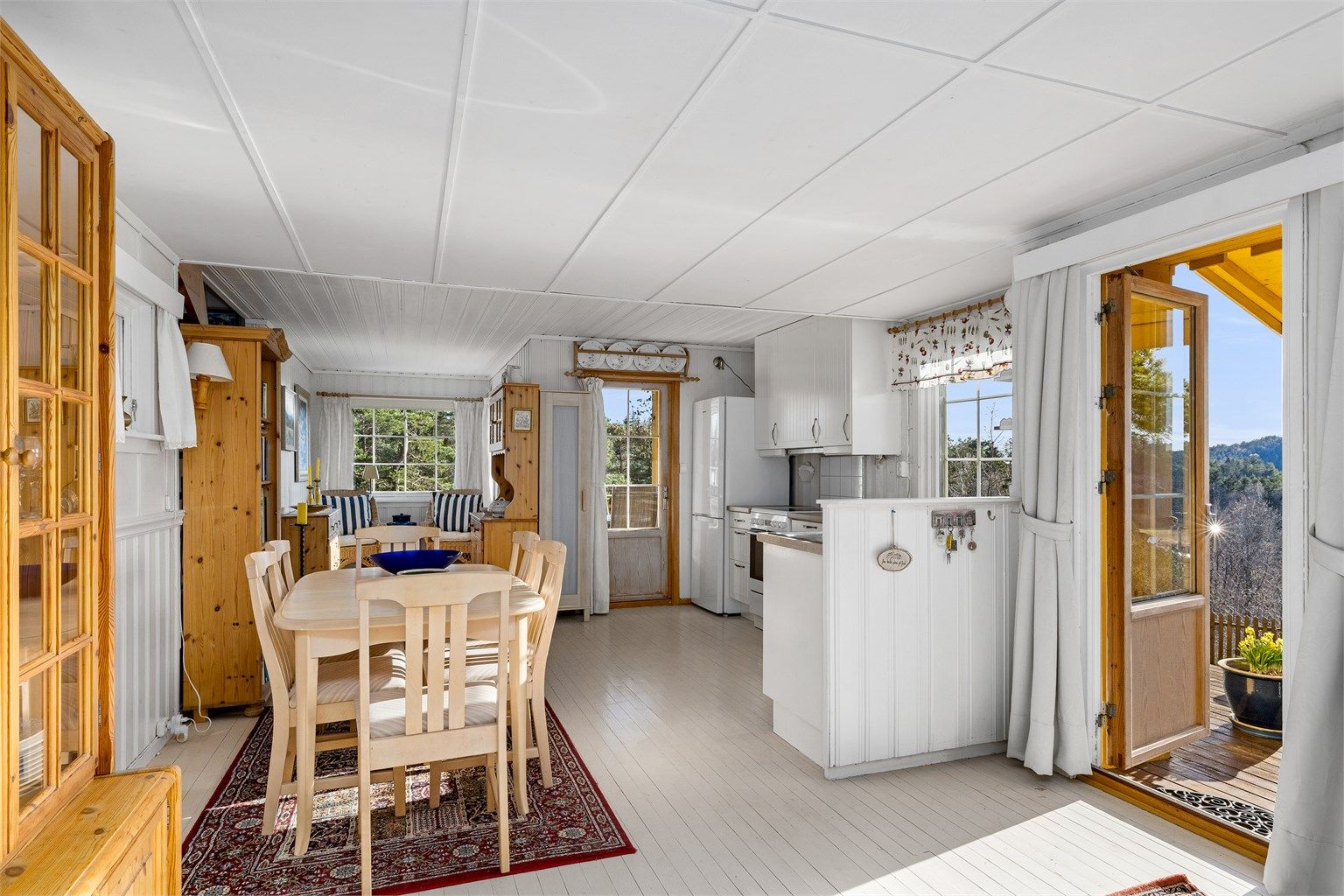 Oppholdsrommet med flere vinduer og utgangsdører med glassfelt gjør stuen og kjøkkenet til et lyst og godt sted å oppholde seg.