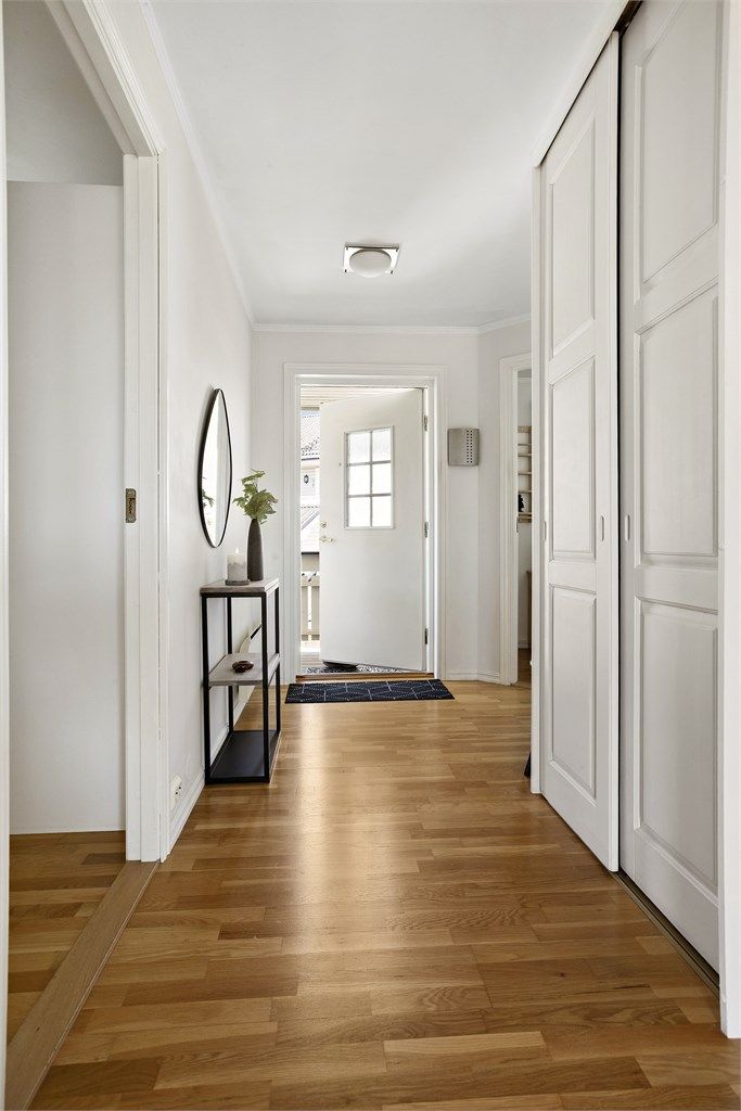 Romslig entré med en stor skyvedørsgarderobe for oppbevaring. Dør med glassfelt slipper lyset videre inn i stuen.