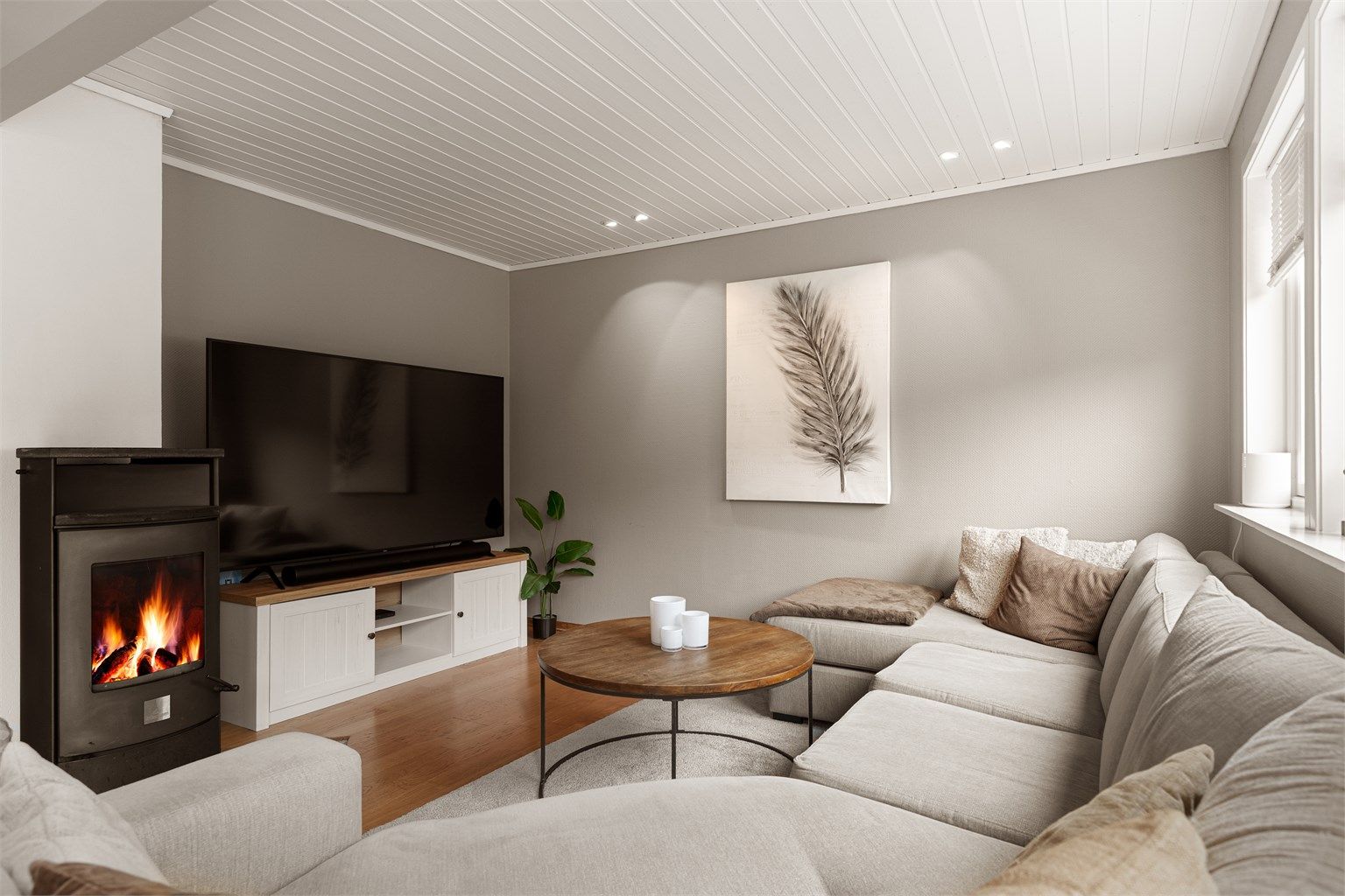 Lun sofakrok ved peisovnen med innfelte downlights i himlingen.