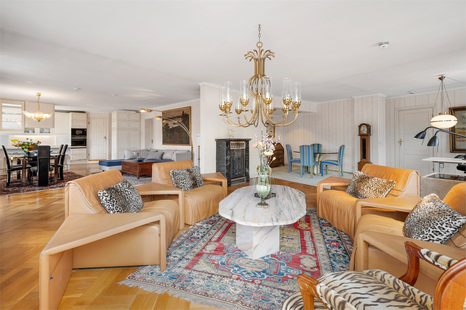 Stue, kjøkken og spisestue ligger i vinkel i et stort, åpent rom.