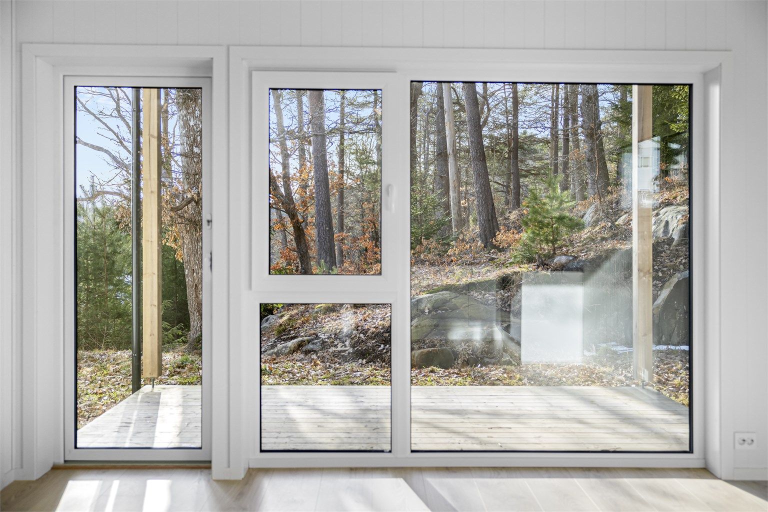 Store vindusflater som gir godt med naturlig lys inn i leiligheten og lite innsyn med naturen i utsynet.