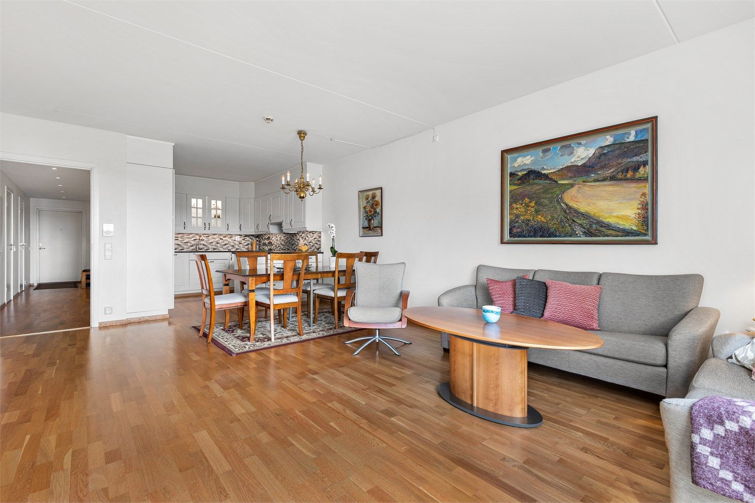 Lys og romslig stue med åpen løsning mot kjøkken og spisestue.