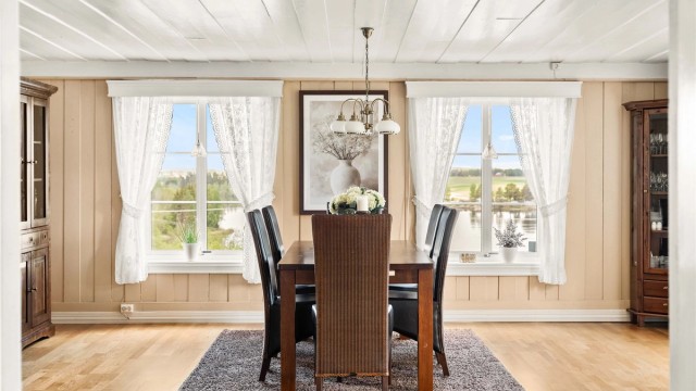 Spisestuen har plass til et stort spisebord og har utsikt mot eiendommens uteområder.