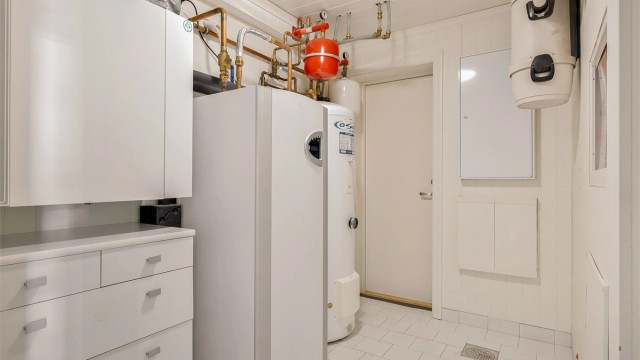 Teknisk rom med varmepumpe for bergvarme, varmtvannstank og sikringsskap.