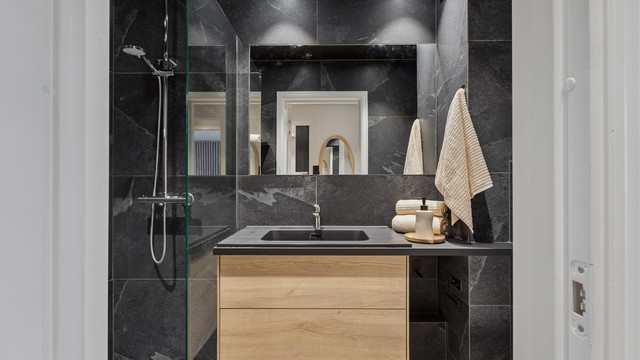 Badet har flislagte overflater, gulvvarme og innredning fra HTH.