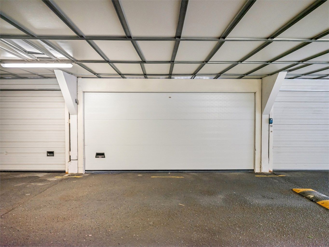 Garasjeplassen er lukket med automatisk leddport, og er plassert like ved døren til blokken. Porten er dobbel og deles med naboen
