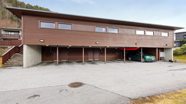 Parkering i egen carport med installert elbillader. Her er det også en praktisk utebod på 5 m².
