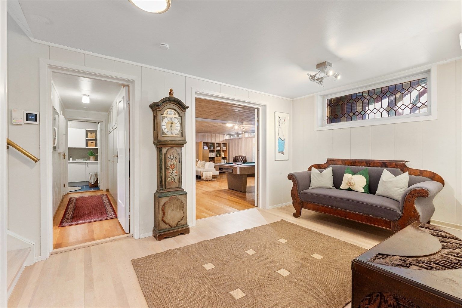 Hallen i underetasjen har heltre eikestaver på gulvet og forbinder flere av rommene.