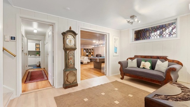 Hallen i underetasjen har heltre eikestaver på gulvet og forbinder flere av rommene.