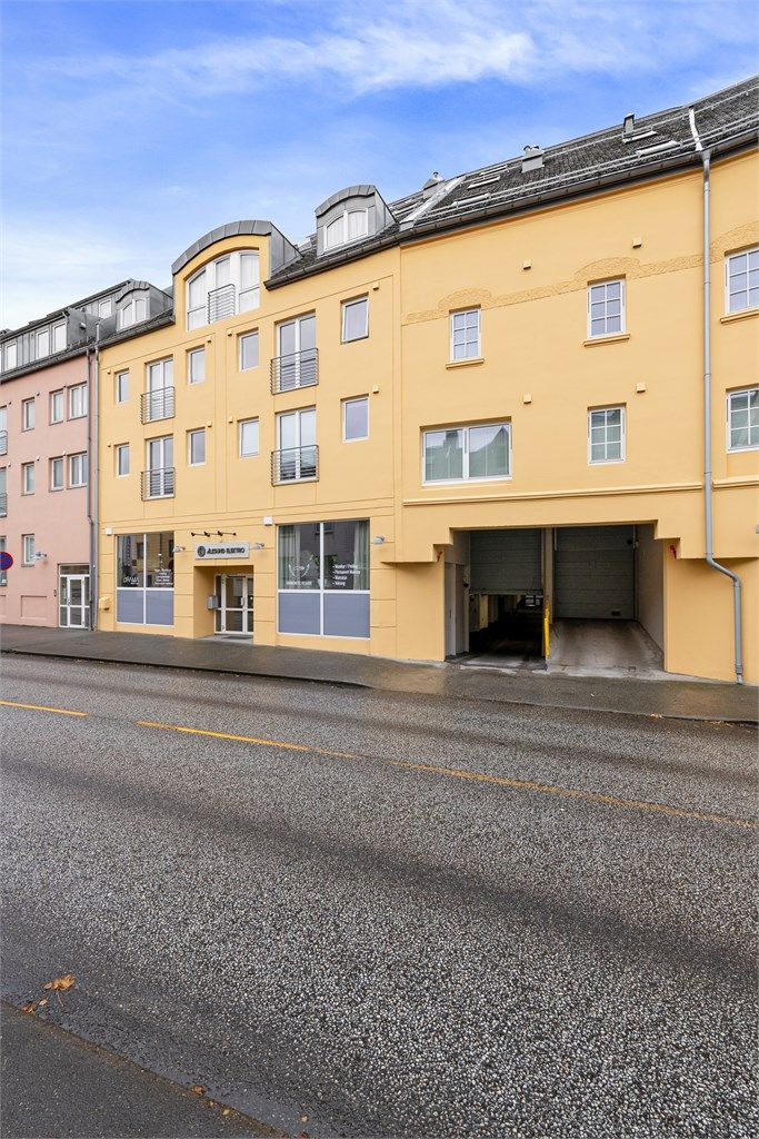 Innkjøring til byggets lukkede garasjeanlegg med fast parkeringsplass og elbillader.