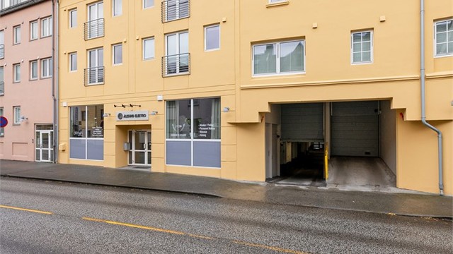 Innkjøring til byggets lukkede garasjeanlegg med fast parkeringsplass og elbillader.