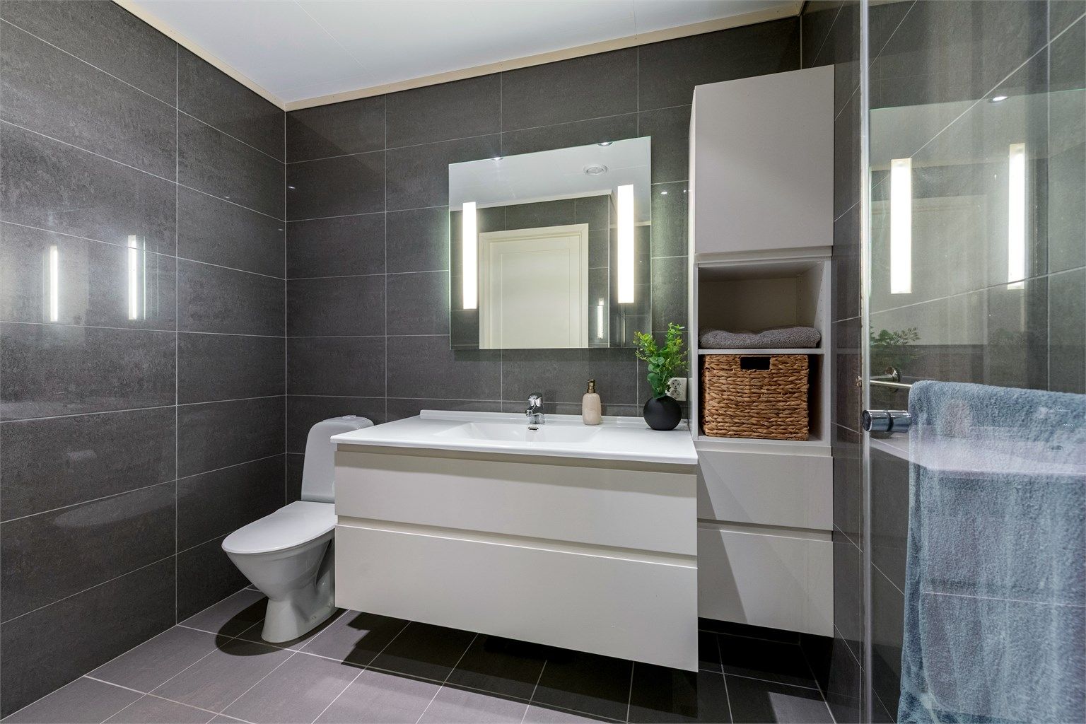 Badet er helfliset, utstyrt med gulvvarme og en romslig servantinnredning.