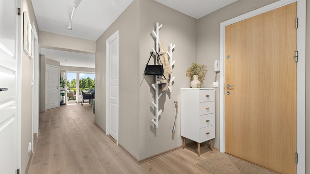 Entré med plass til mindre kommode eller hyller. Fra entreen er det tilgang til et av soverommene, kjøkkenet, toalettrommet, badet, stuen og garderoben.