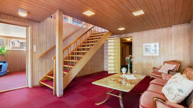 Innvendig trapp i tre med teppebelagte trinn forbinder de to etasjene. Både hall og kjellerstue er belagt med teppeflis på gulv.