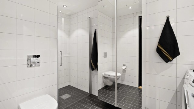 Pent, flislagt bad med dusjhjørne og moderne innredning.