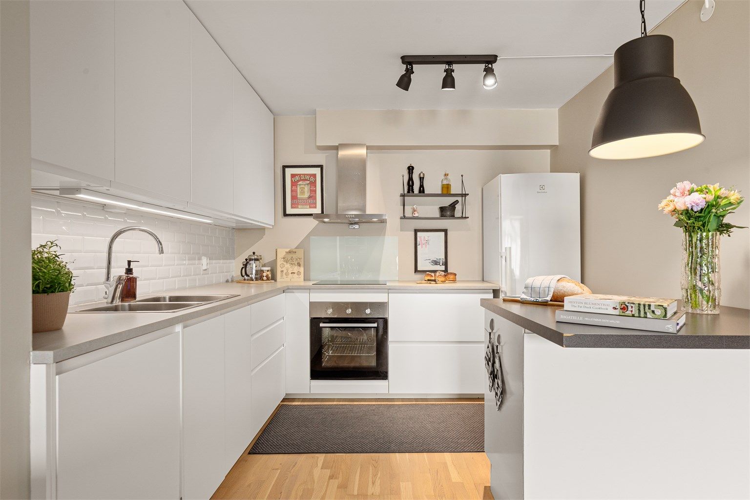 Pent innredet kjøkken med integrerte hvitevarer og praktisk kjøkken-halvøy mot stuen