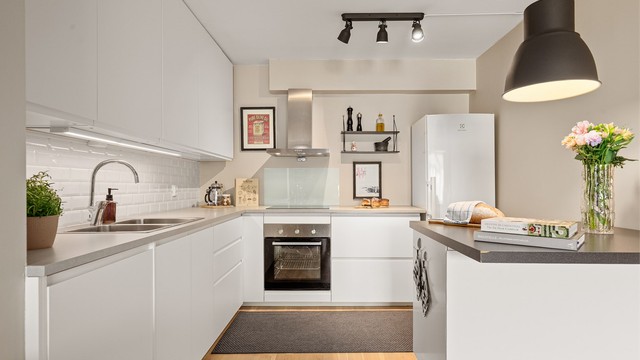 Pent innredet kjøkken med integrerte hvitevarer og praktisk kjøkken-halvøy mot stuen