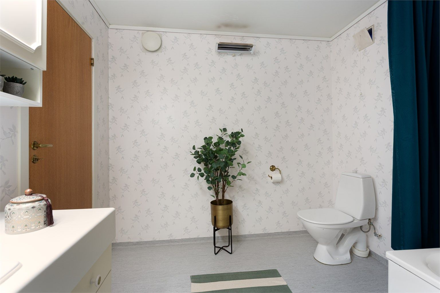 Badet har gulvbelegg, tapetserte vegger og malt himling.