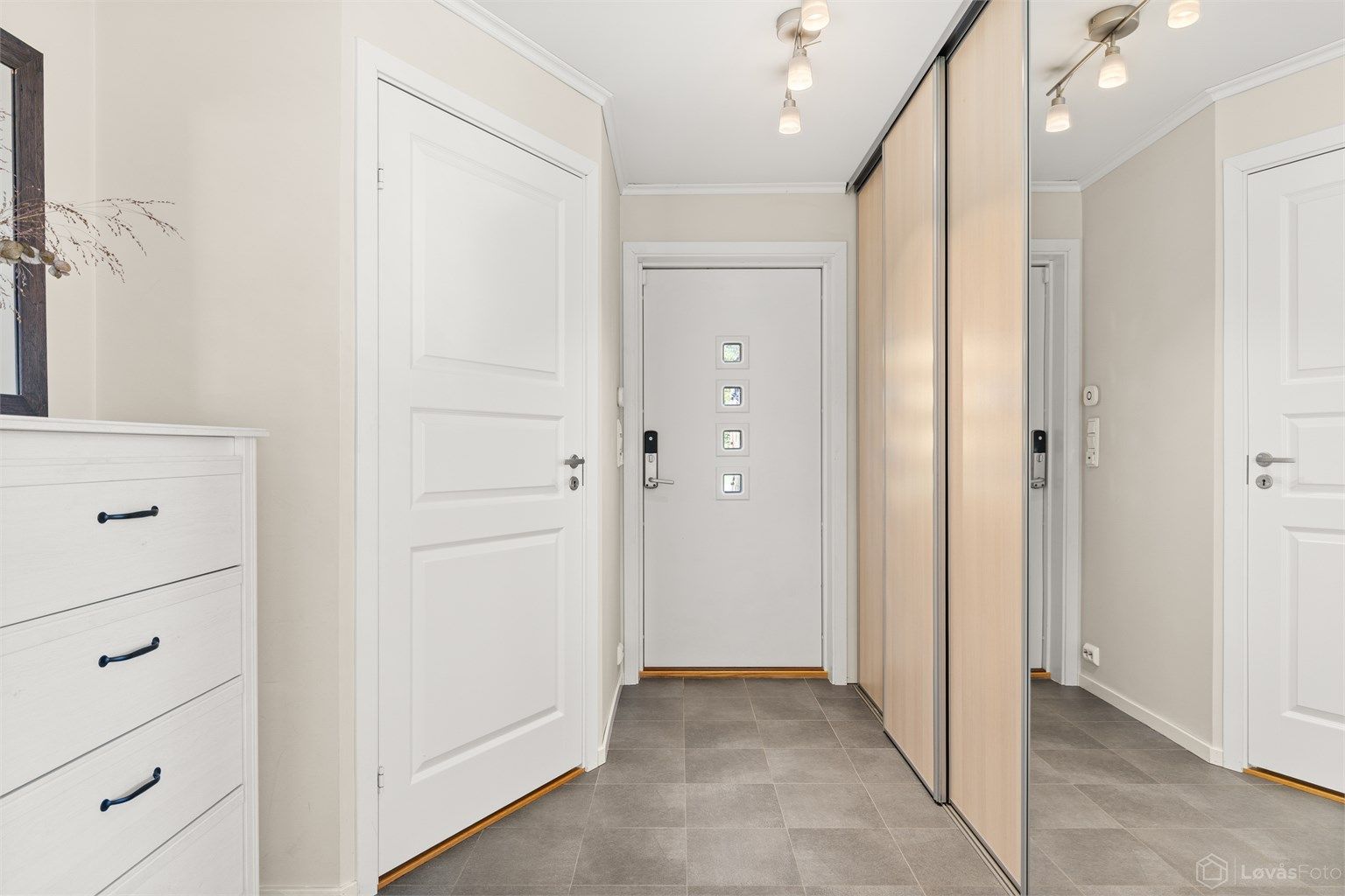 Romslig entrémed gulvfliser med gulvvarme og stor skyvedørsgarderobe med rikelig med garderobeplass