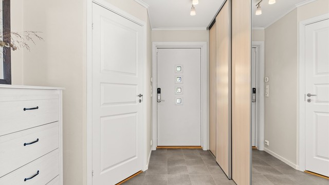 Romslig entrémed gulvfliser med gulvvarme og stor skyvedørsgarderobe med rikelig med garderobeplass