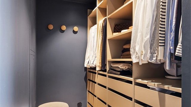 Walk-in garderobe med åpen garderobeløsning som har hyller, klesskinner og skuffer.