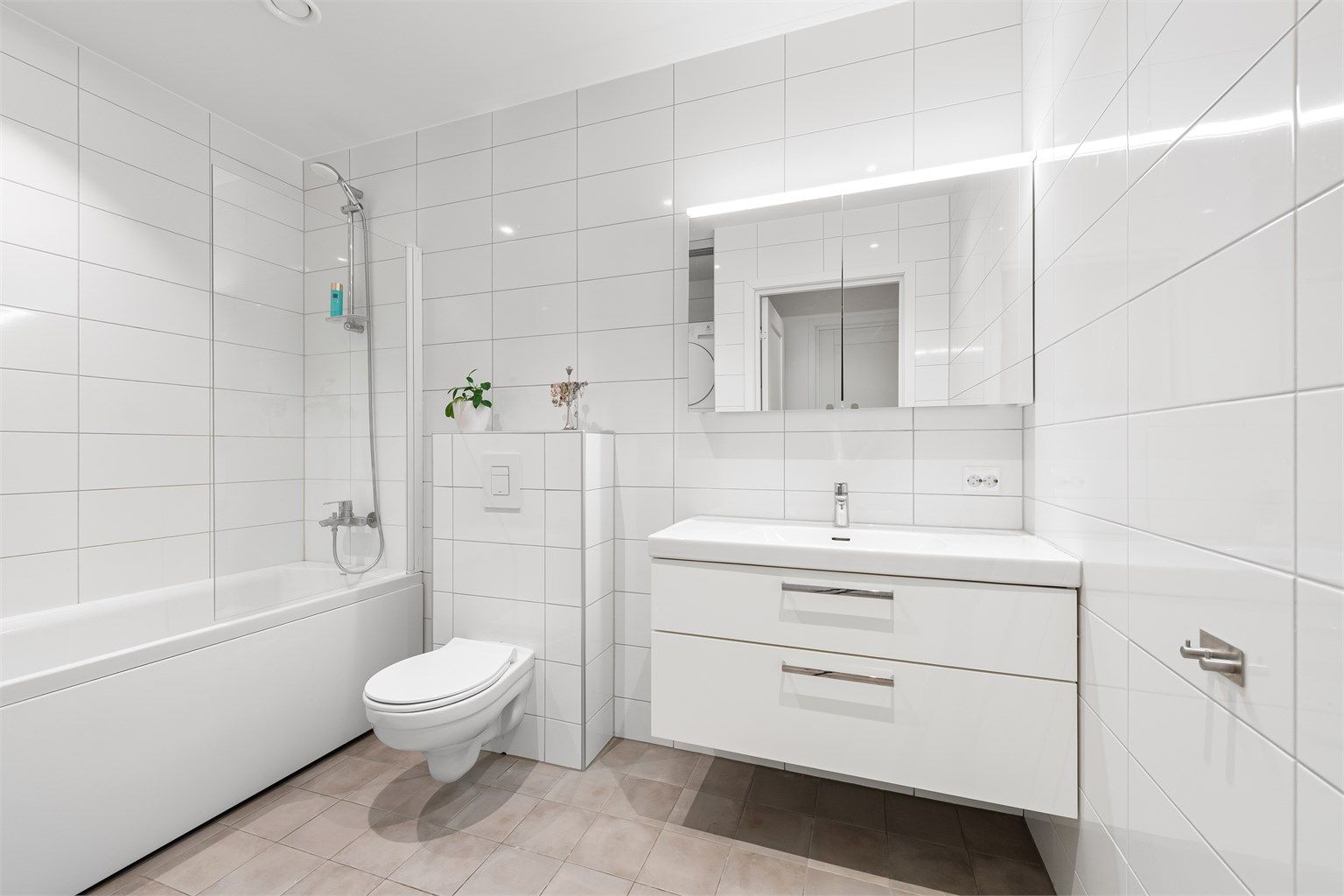 Romslig og helfliset bad med gulvvarme, innredning fra Svedbergs og badekar med dusjvegg.