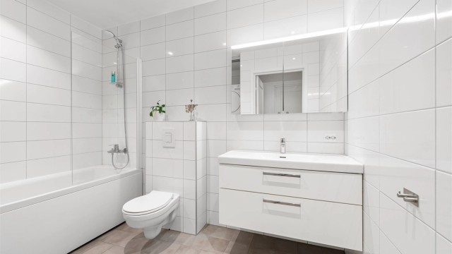Romslig og helfliset bad med gulvvarme, innredning fra Svedbergs og badekar med dusjvegg.