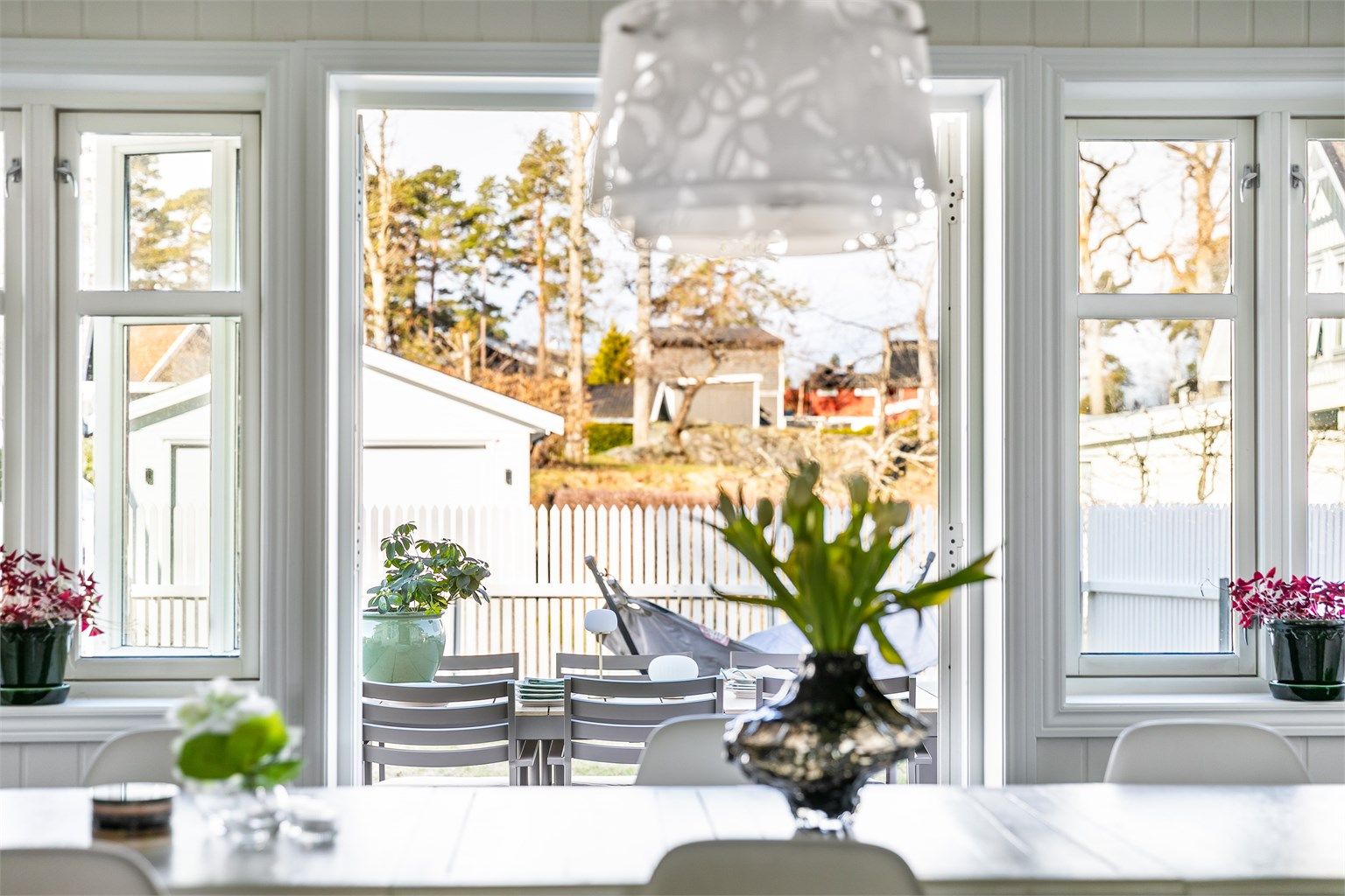 Fløydør åpner stuen mot uteplassen. To-rams sprossevinduer underbygger en klassisk atmosfære.