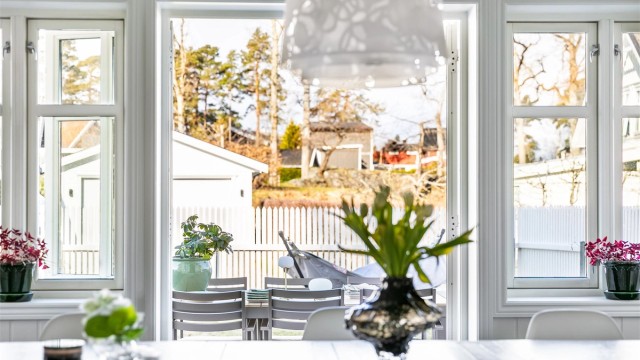 Fløydør åpner stuen mot uteplassen. To-rams sprossevinduer underbygger en klassisk atmosfære.