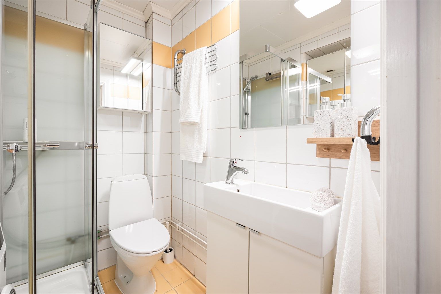 Det er speil med overlys over vasken og speilskap på vegg over toalettet.