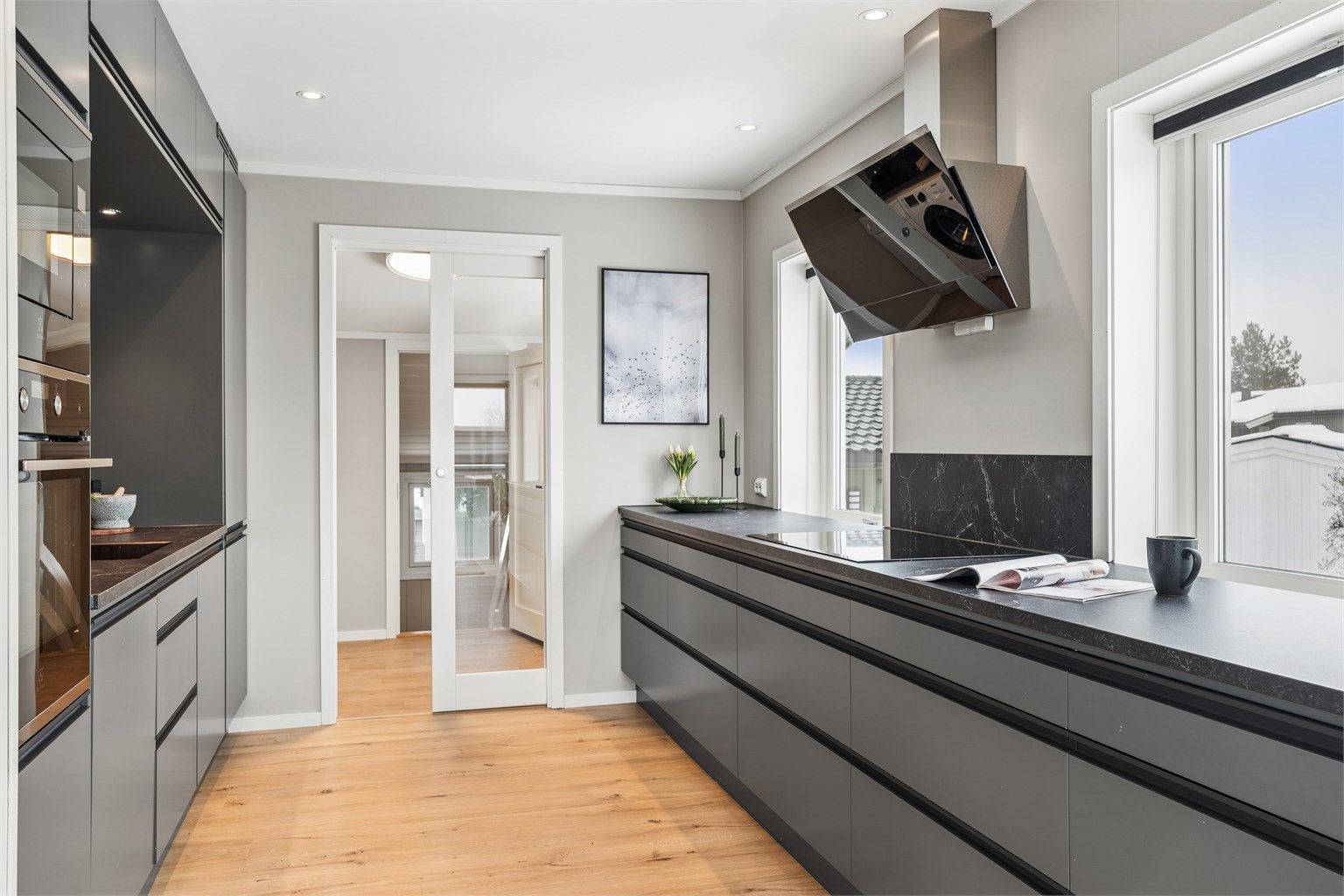 Her er det en åpen kjøkkenløsning med innredning fra 2021 med glatte fronter, integrerte hvitevarer og gode arbeidsflater.