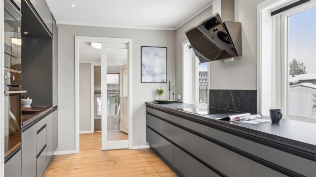 Her er det en åpen kjøkkenløsning med innredning fra 2021 med glatte fronter, integrerte hvitevarer og gode arbeidsflater.