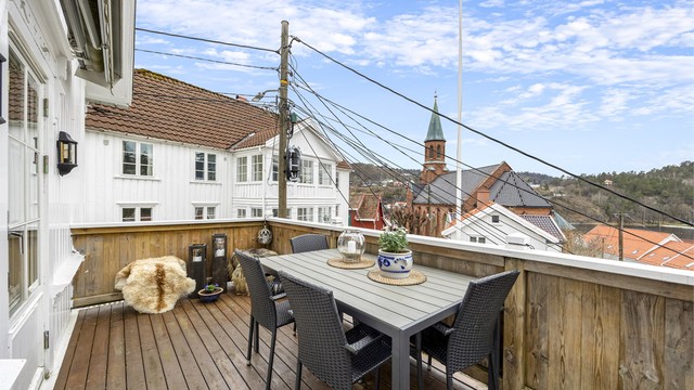 Flott veranda fra 2003 med kveldssol og utsikt. Det er montert markise på husveggen.