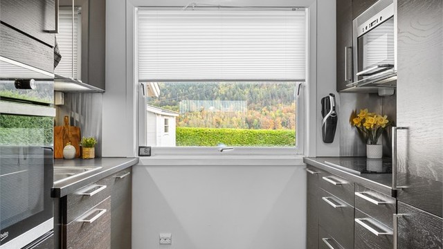 Pent kjøkken med innredning fra 2009 med glatte fronter. Benkeplate med laminert overflate med nedfelt kjøkkenvask.