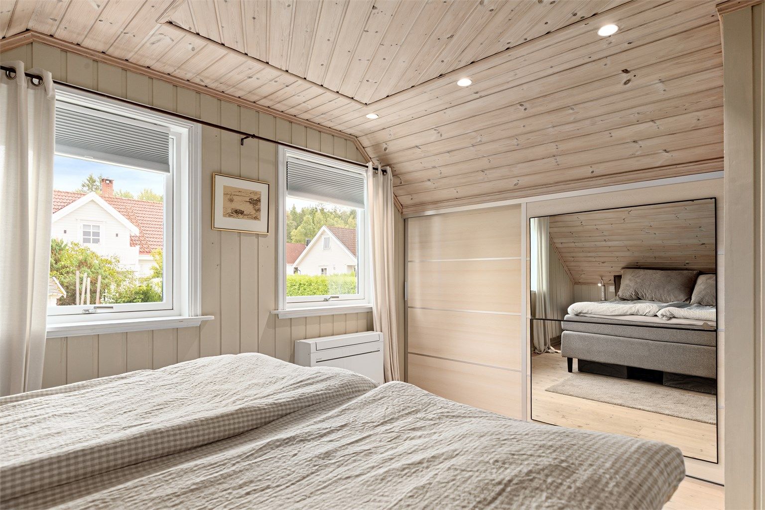 Integrert skyvedørsgarderobe med speilfront og innfelte downlights i himlingen.