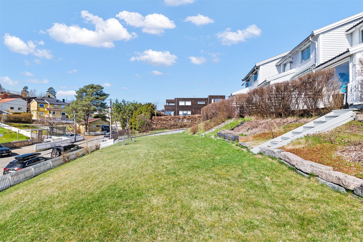 Tomten er svakt skrånende og opparbeidet med plenarealer og beplantning.