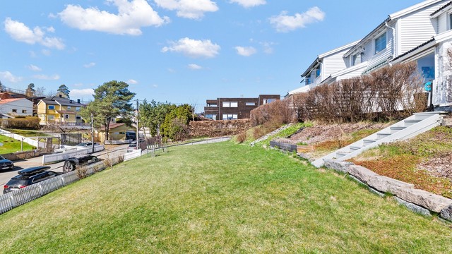 Tomten er svakt skrånende og opparbeidet med plenarealer og beplantning.