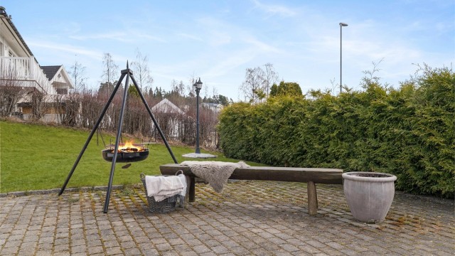 Uteområdet er pent opparbeidet med en romslig gårdsplass belagt med belegningsstein, fine plenarealer og hekker rundt eiendommen.