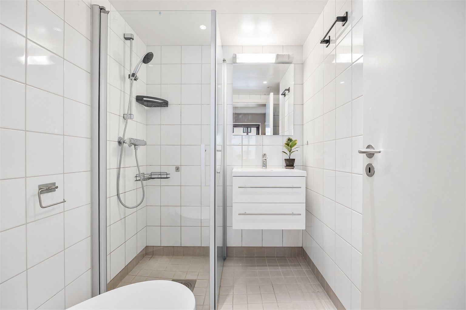 Flislagt baderom med gulvvarme. Badet er innredet med vegghengt servantinnredning og speil med overlys.