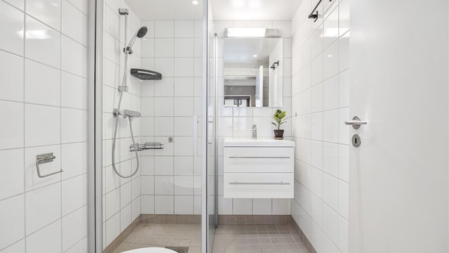 Flislagt baderom med gulvvarme. Badet er innredet med vegghengt servantinnredning og speil med overlys.
