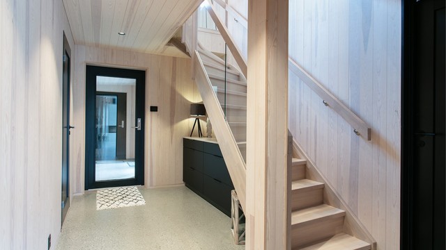 Hall med innvendig tretrapp og glassrekkverk opp til loftsetasjen.