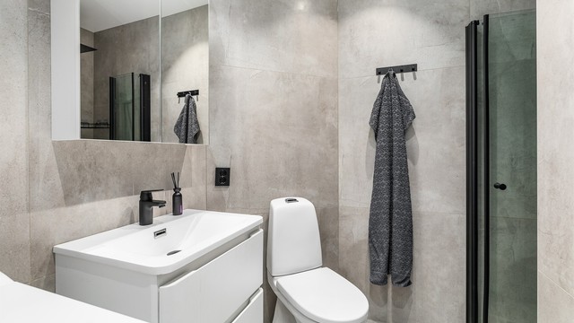 Etter ombygging og oppgradering i 2022 er badet stilfullt og moderne. Like fliser på gulv og vegger skaper helhet, sorte elementer danner kontrast.