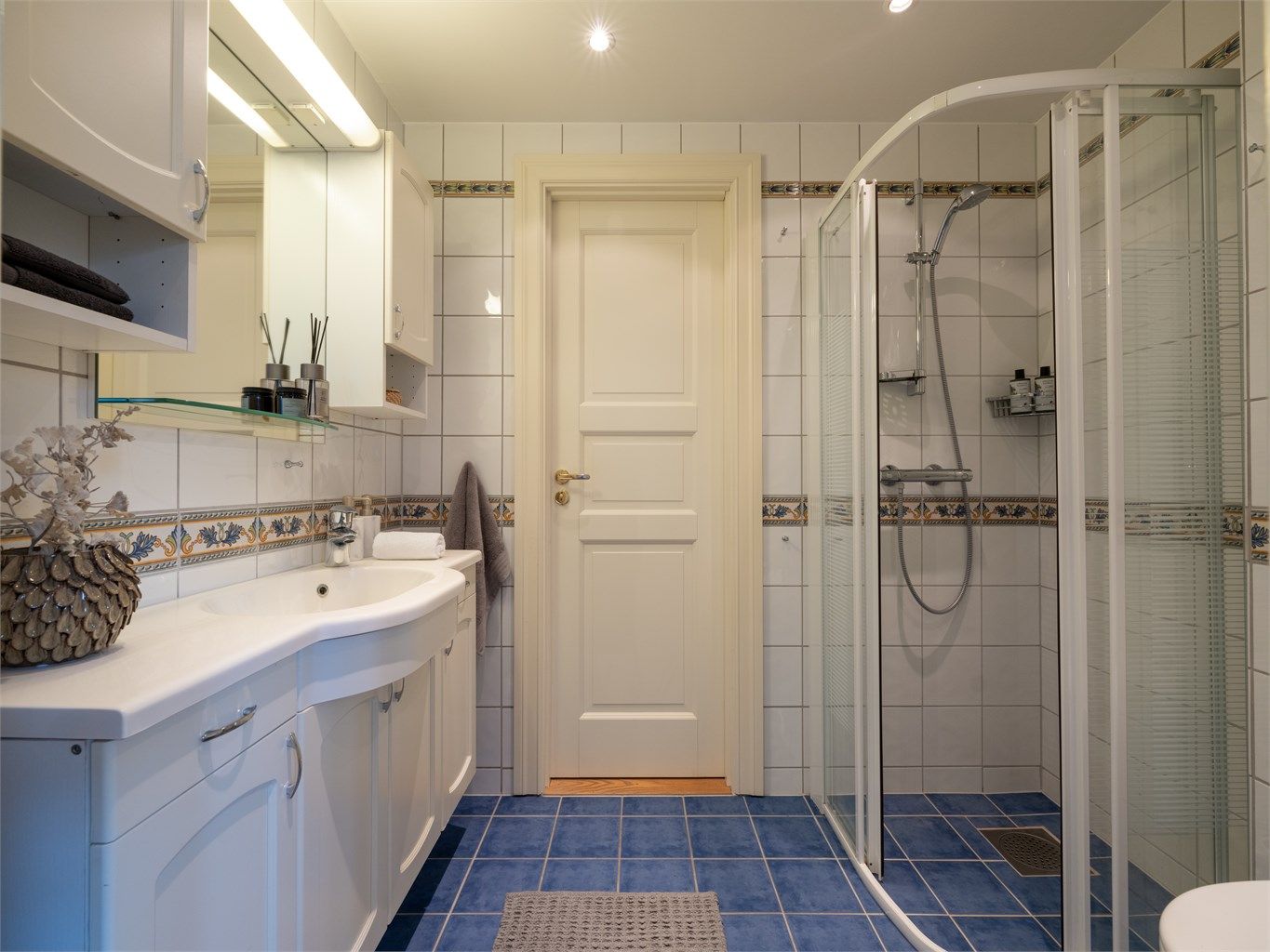 Det er egen dusjsone med skyvedører i glass og vegghengt toalett.