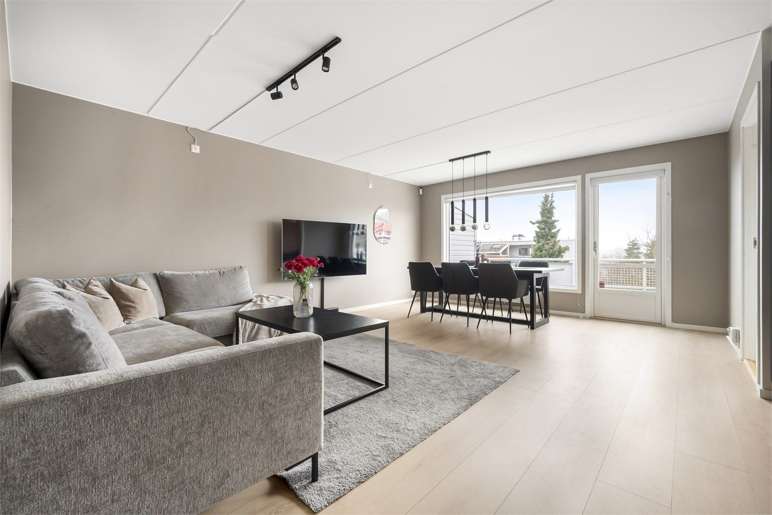 Leiligheten har en åpen og sosial planløsning mellom stue og kjøkken, med gjennomgående gulv som binder rommene sammen.