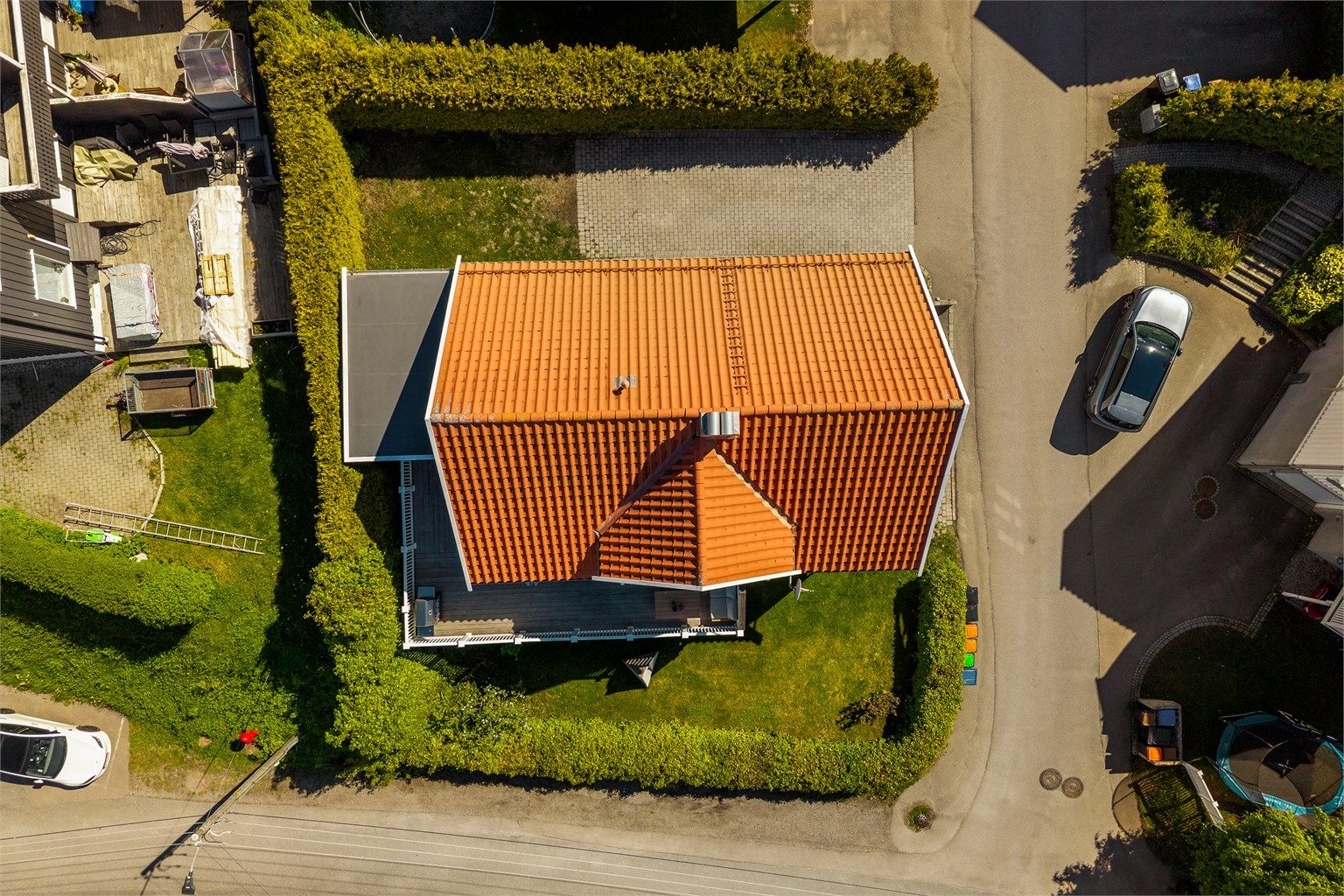 Tomten er skjermet med hekk og har en fin beliggenhet på et hjørne, og lite innsyn da eneboligen ligger nederst.