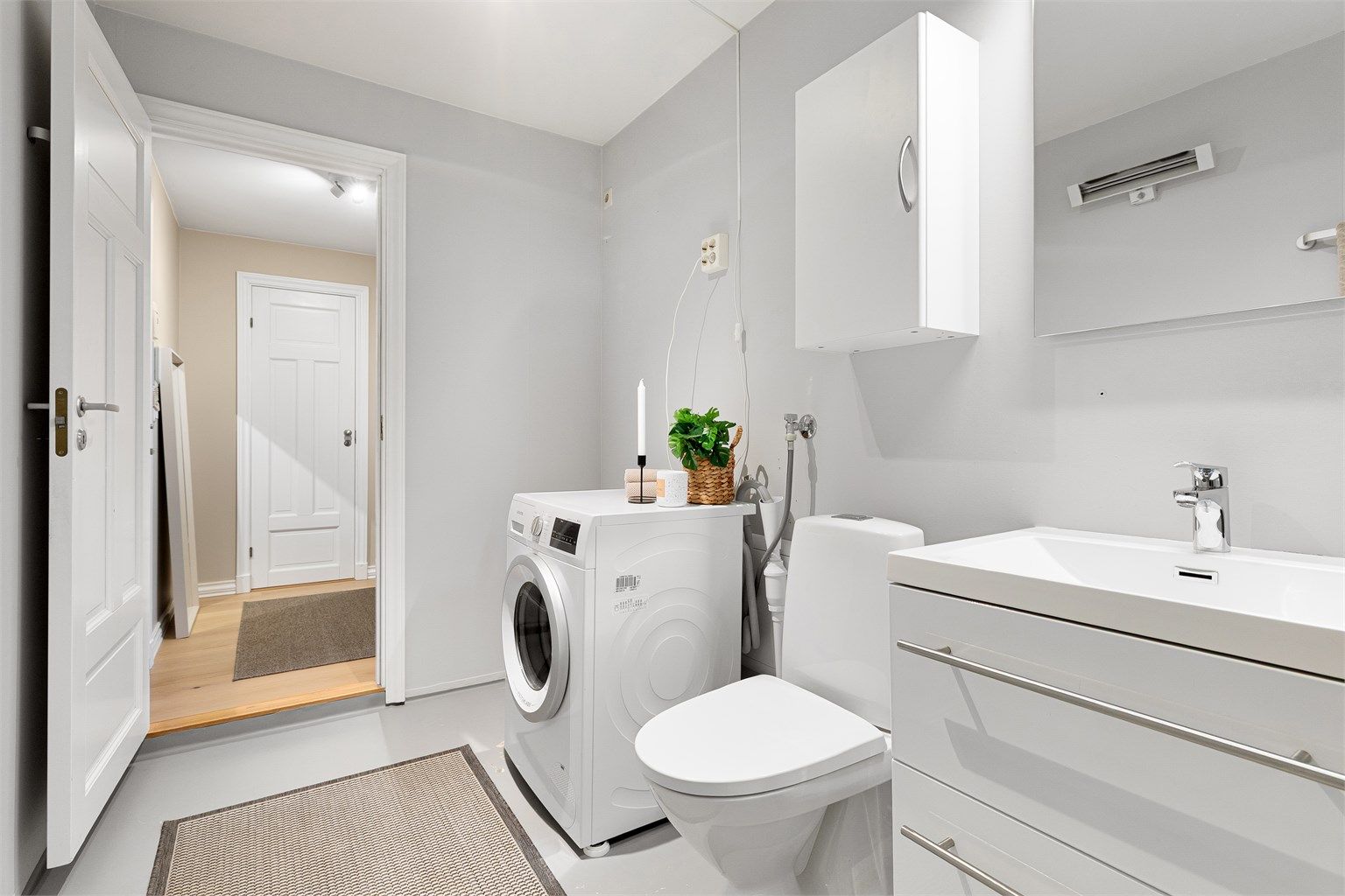 Innredningen består av en vegghengt servant med skuffer, speil med overlys og et vegghengt skap.