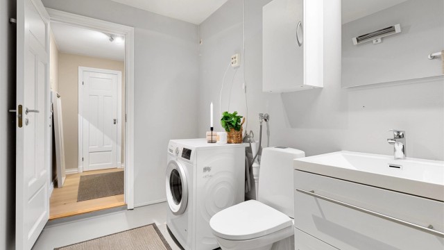 Innredningen består av en vegghengt servant med skuffer, speil med overlys og et vegghengt skap.