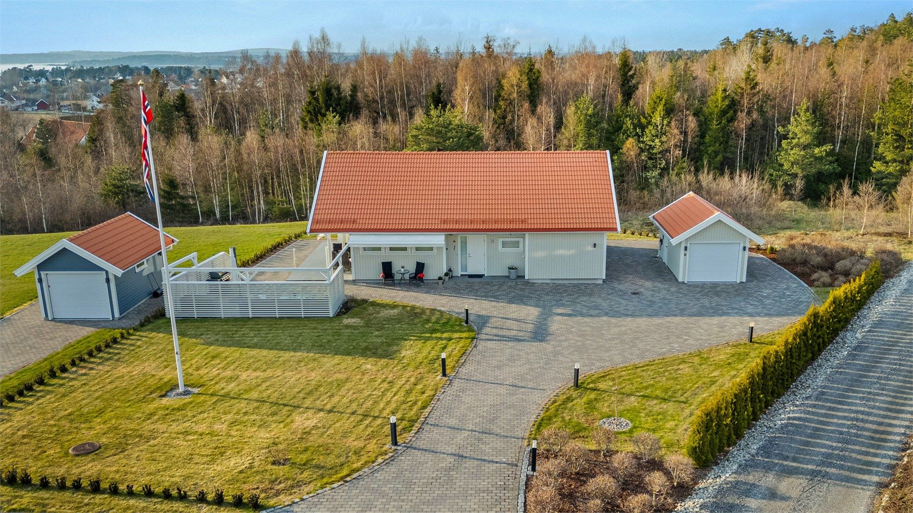 Eiendommen har en innbydende, brosteinlagt gårdsplass på ca. 150 kvm, samt brostein rundt både boligen og garasjen – noe som gir et helhetlig og ryddig uttrykk. Garasjen ble oppført samtidig med boligen og har plass til én bil, i tillegg til oppbevaring.