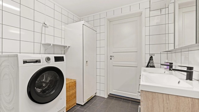 Baderommet er flislagt og har elektrisk gulvvarme for økt komfort. Dobbelt servantskap og praktisk opplegg for vaskemaskin.