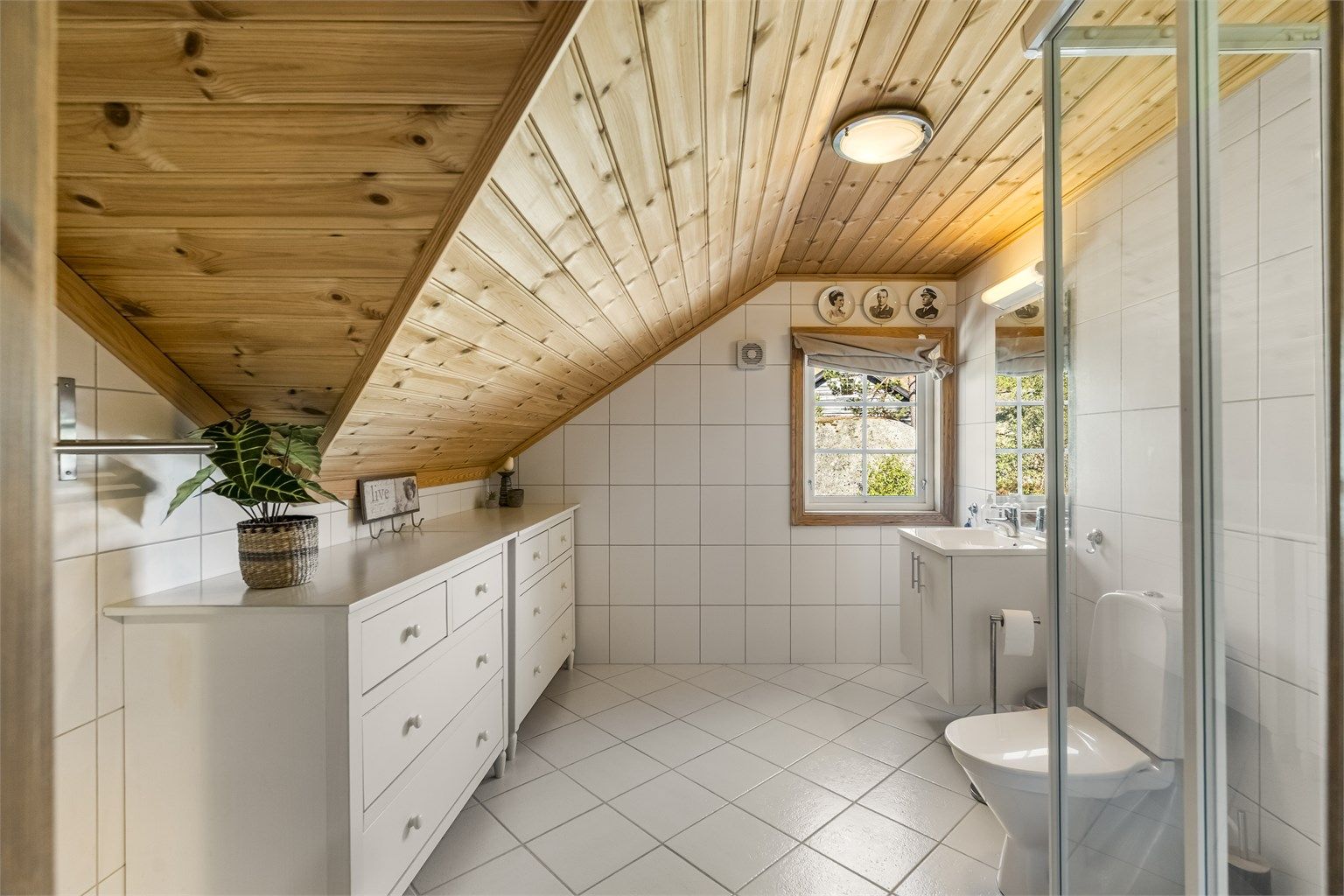 Badet i loftsetasjen har flislagt gulv med gulvvarme og dusjkabinett.